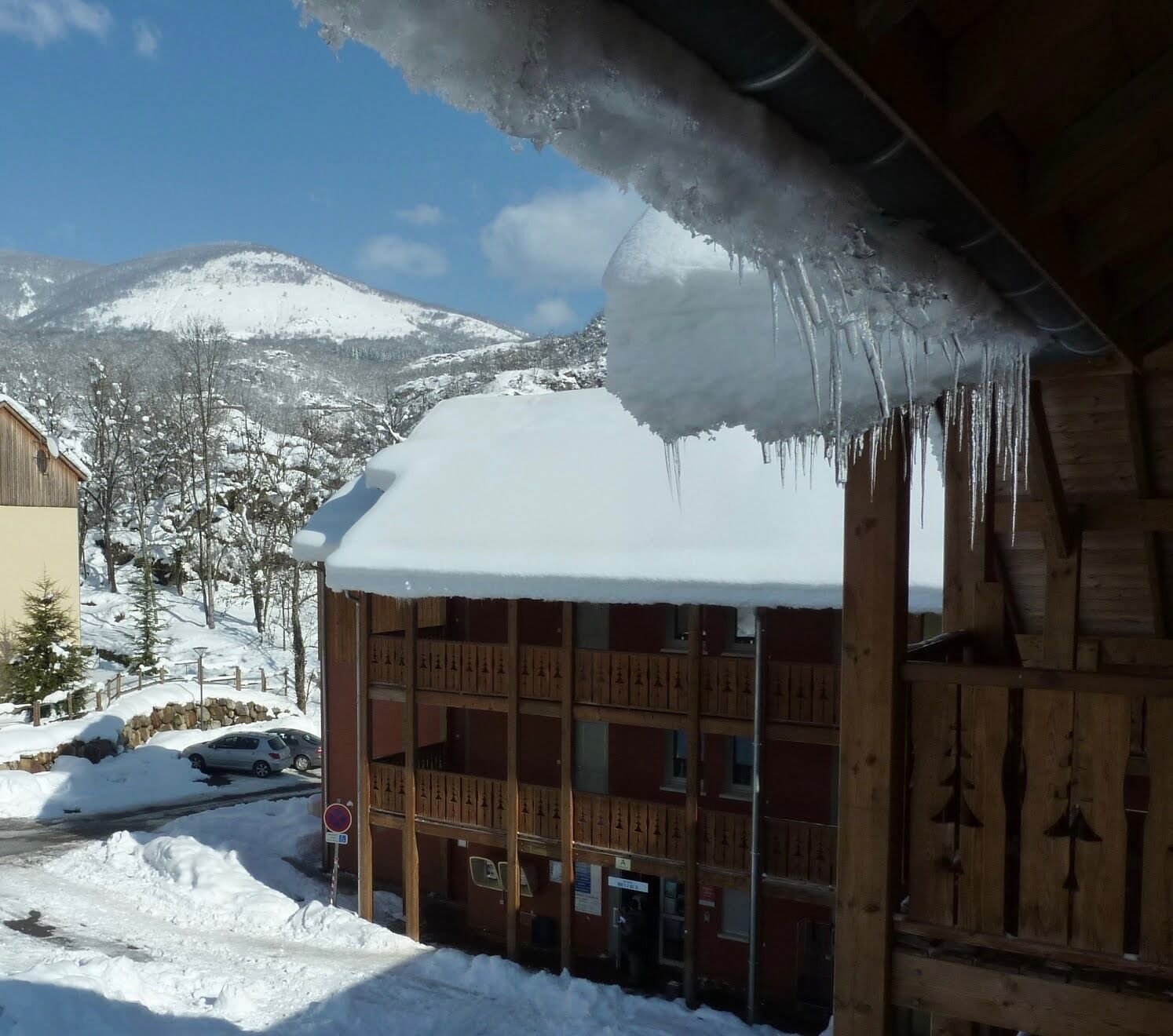 Een houten gebouw met een met sneeuw bedekte dak en zich omlaag hangende icicles.