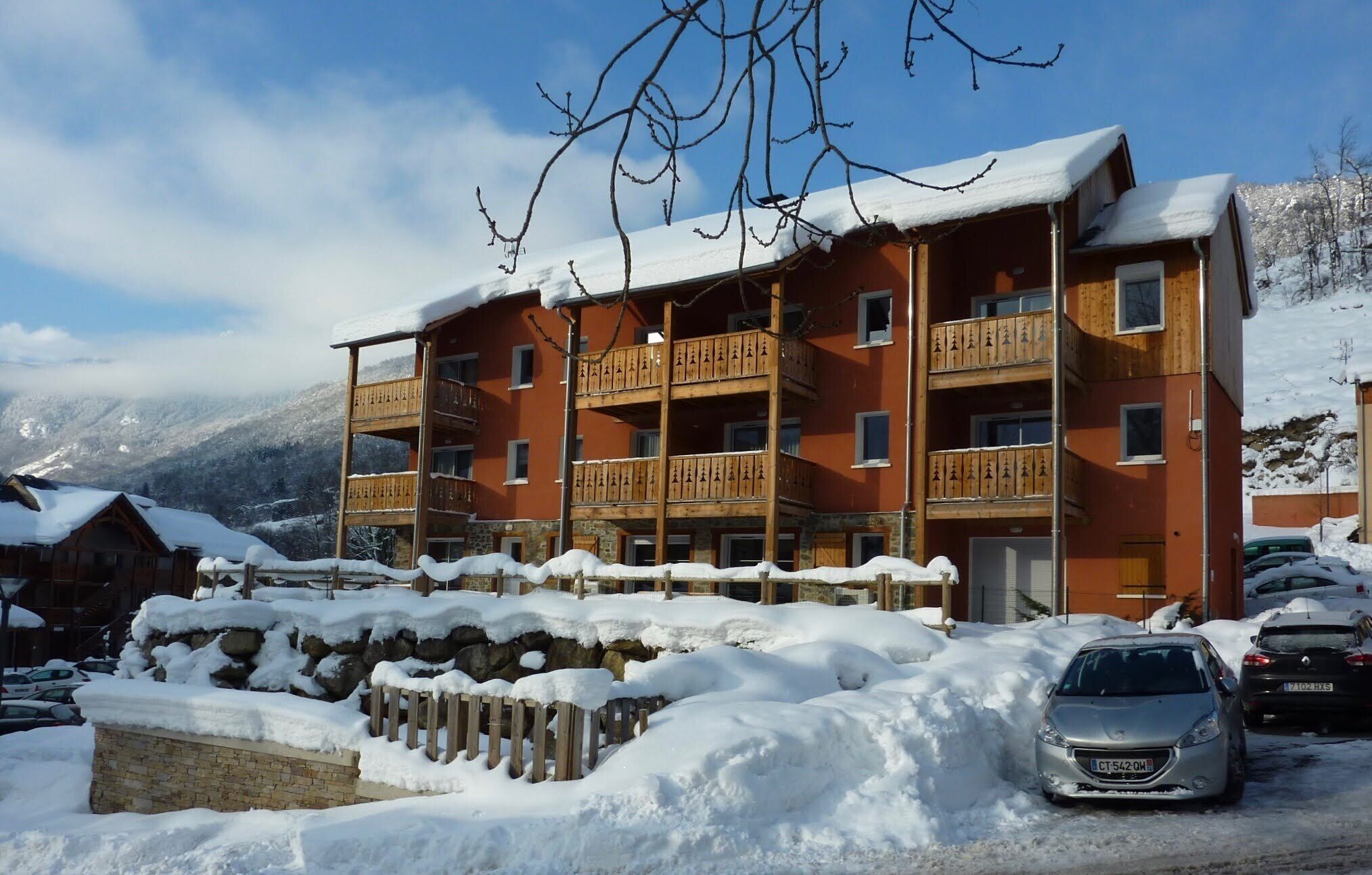 A multi-story hotel with balconies, surrounded by snow-covered mountains.