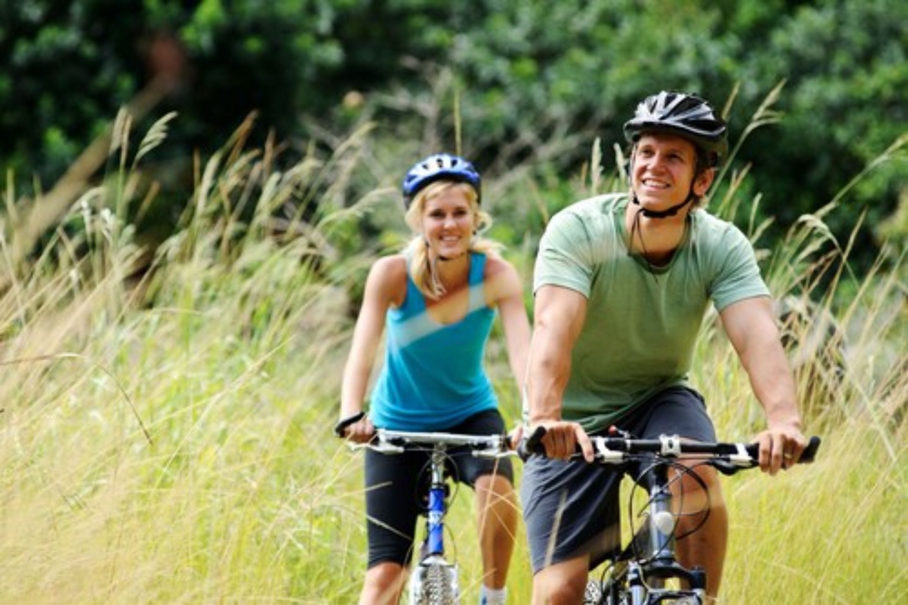 Two people on bicycles in a grassy area.
