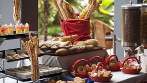 Montaje de bufé con diversos alimentos, como pan, pasteles y bebidas.