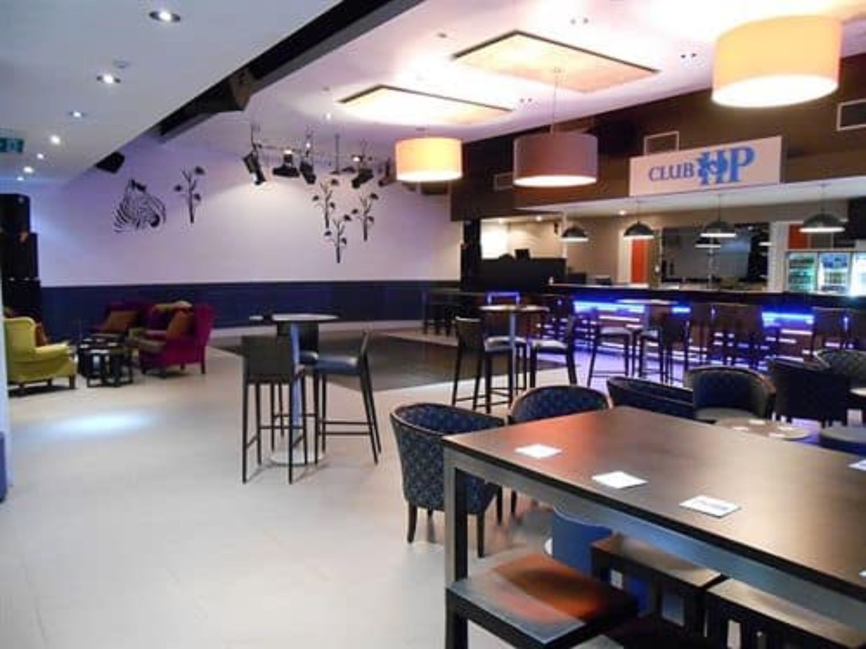 A modern lounge area with bar seating, a counter, and a sign reading "CLUB HP".