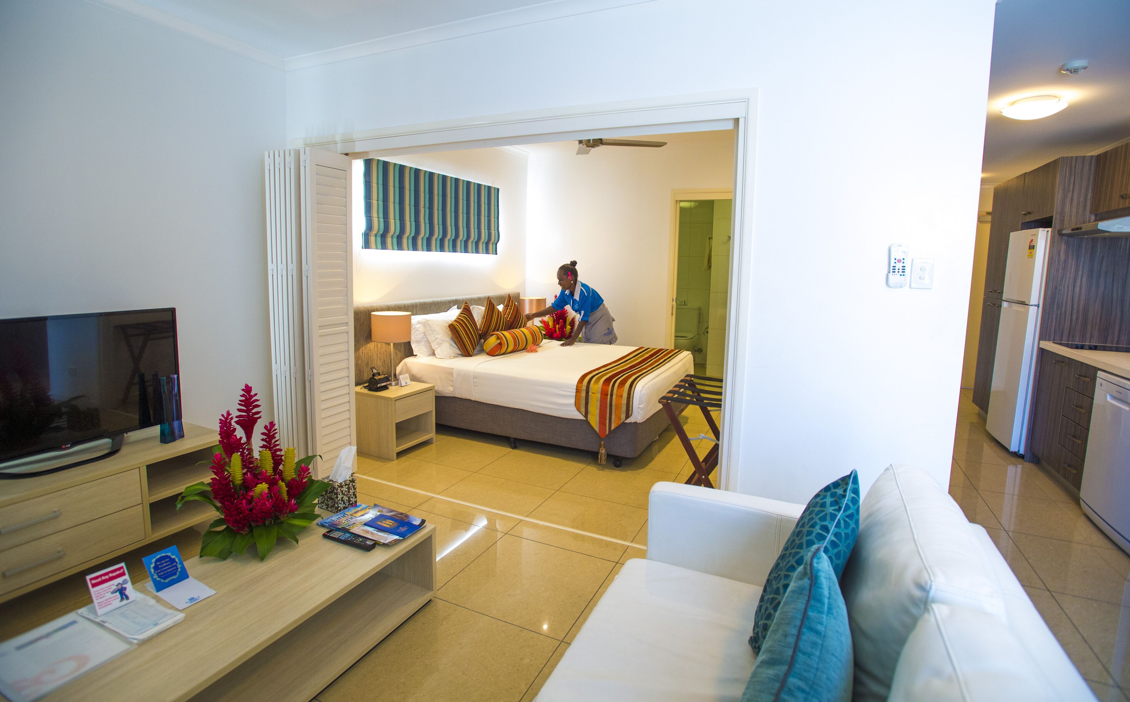 A hotel room with a bed, a TV, a desk, and a bathroom visible through an open door.