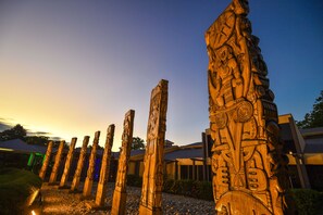 A row of intricately carved wooden pillars in a garden setting. - Heritage Park Hotel (Honiara)