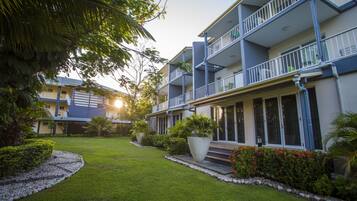 A multi-story hotel with balconies, a well-maintained lawn, and potted plants.