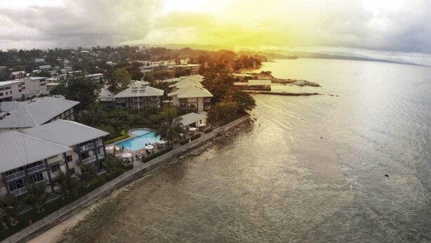 Vista aérea de un hotel frente al mar con piscina y vistas al océano.