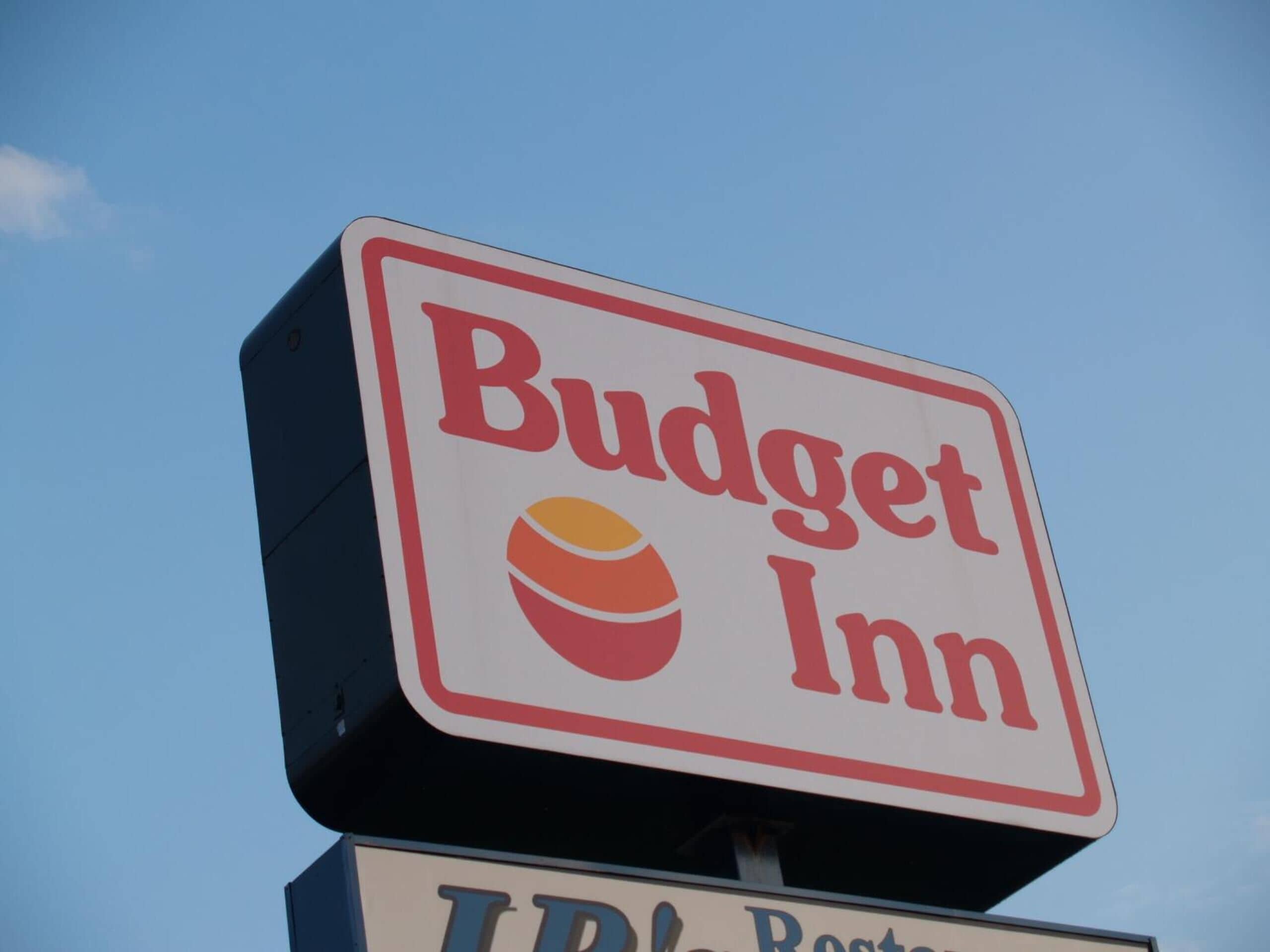 A sign for Budget Inn with a logo of a peach and a bowl.