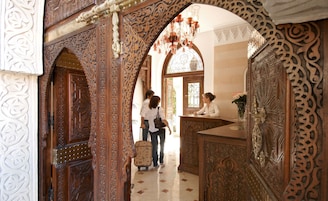 Un lobby ornamentado con detalles de carpintería elaborada, un candelabro y una recepción.