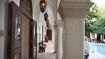 Un pasillo con puertas y columnas decorativas que conduce a una zona de piscina.