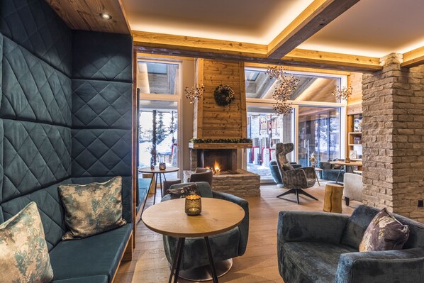Un salon chaleureux avec une cheminée, des sièges confortables et de grandes fenêtres.