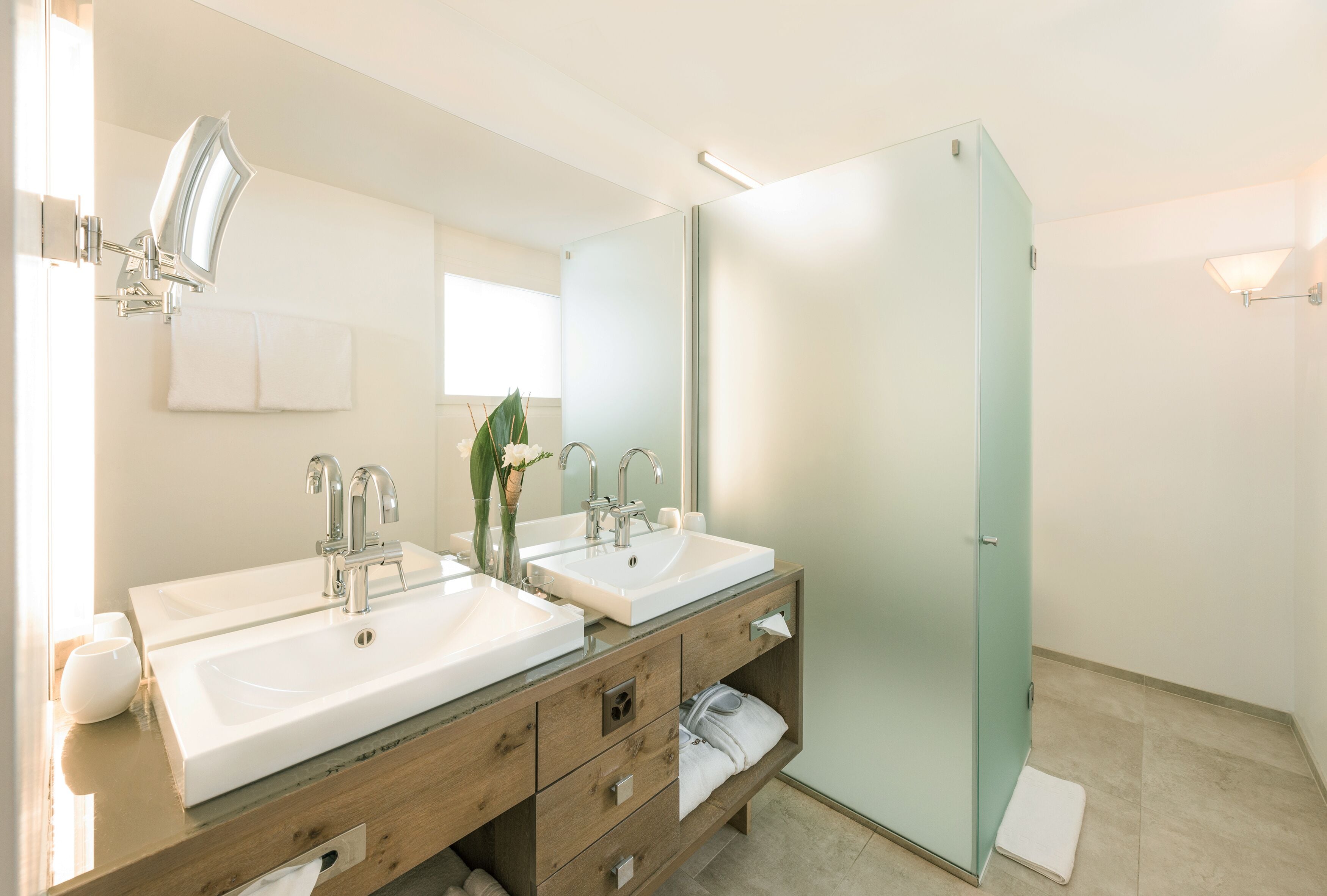 Une salle de bain moderne avec deux lavabos, un miroir et une douche.