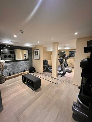 A modern home gym with exercise equipment, a stone accent wall, and a large mirror.