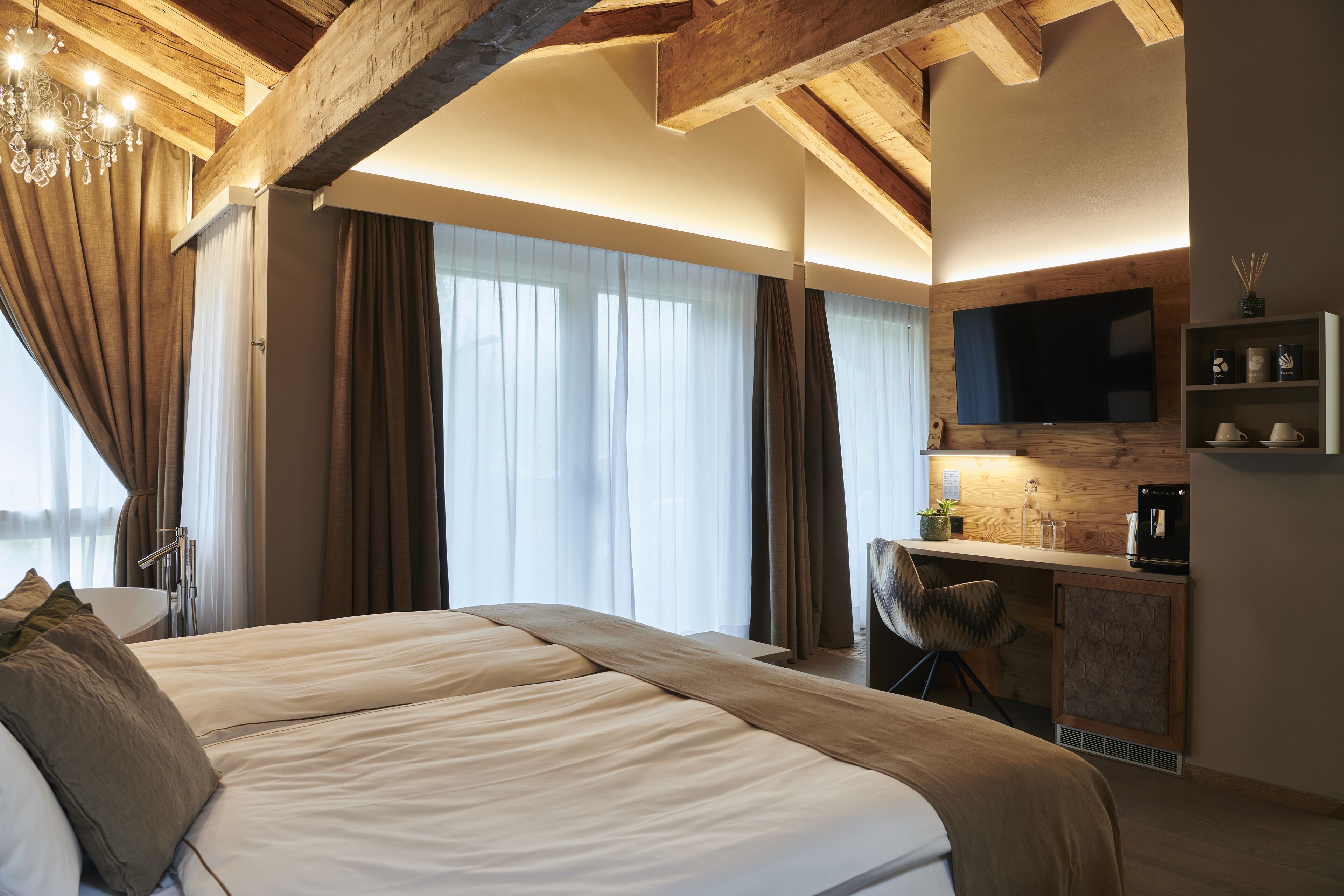 Une chambre d’hôtel moderne équipée d’un grand lit, d’un bureau avec un ordinateur, d’une télévision et d’une kitchenette.