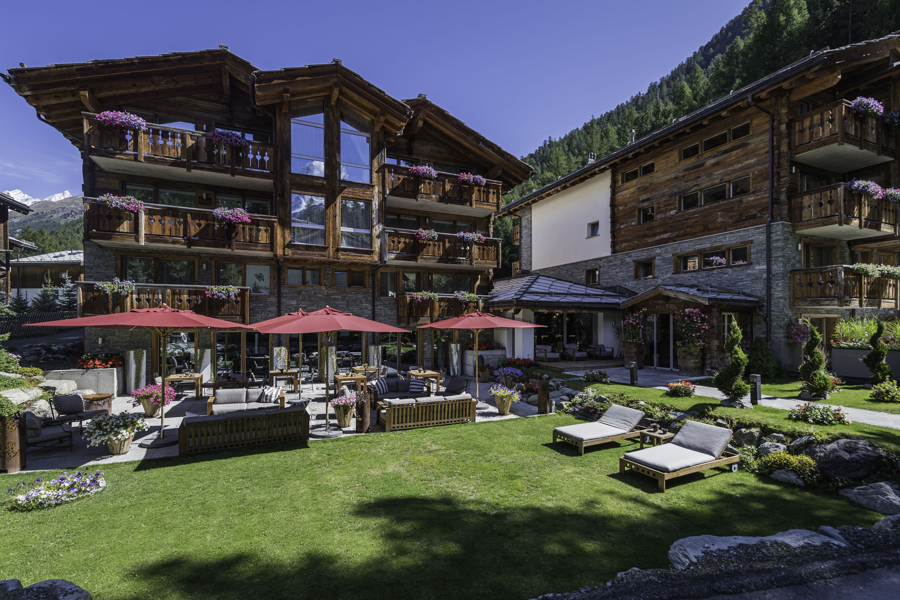 A multi-story wooden building with balconies, outdoor seating, and a well-maintained garden.