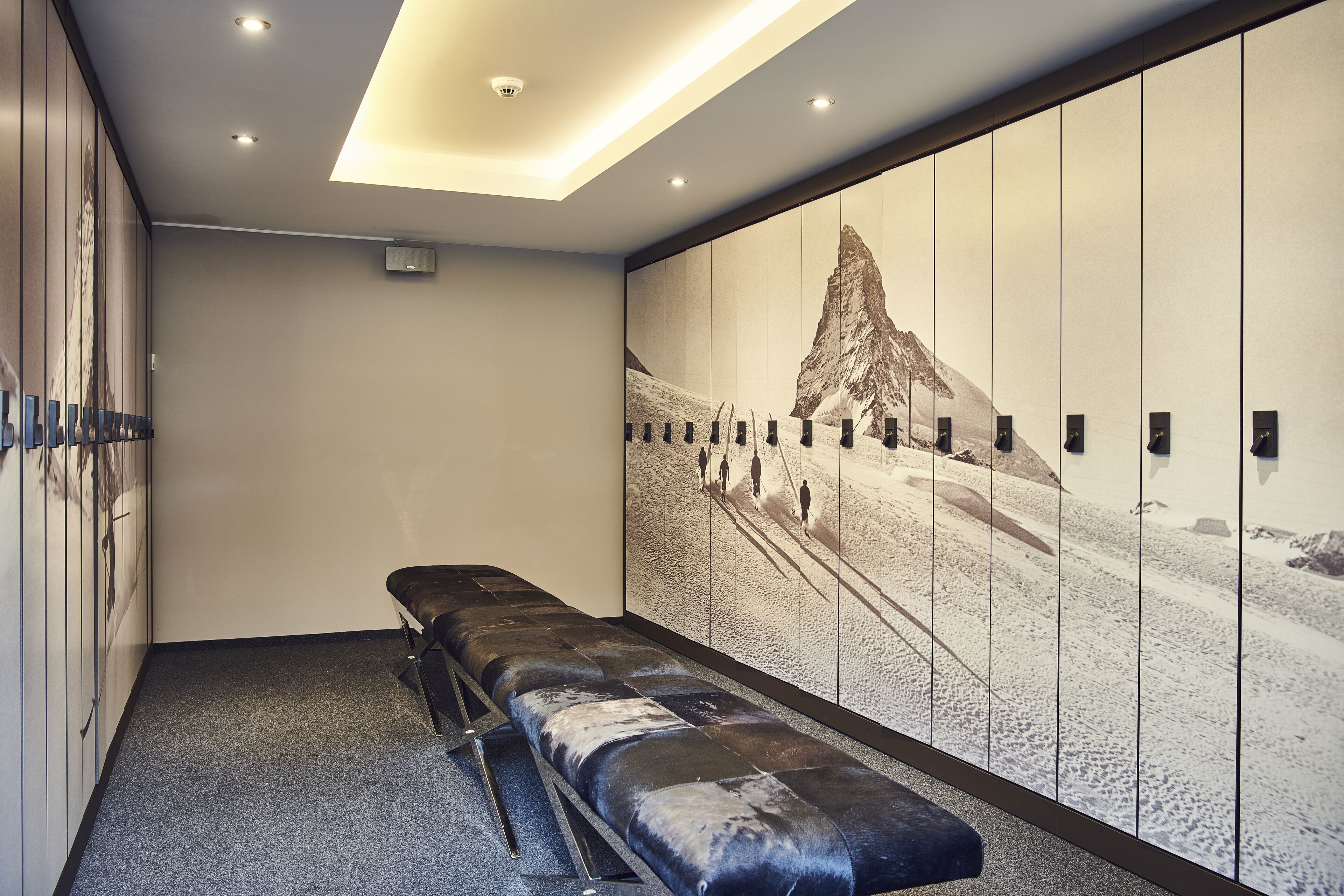A room with a long bench, a wall-mounted picture, and a ceiling light.