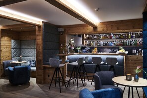 A bar area with wooden beams, bar stools, and a variety of liquor bottles.