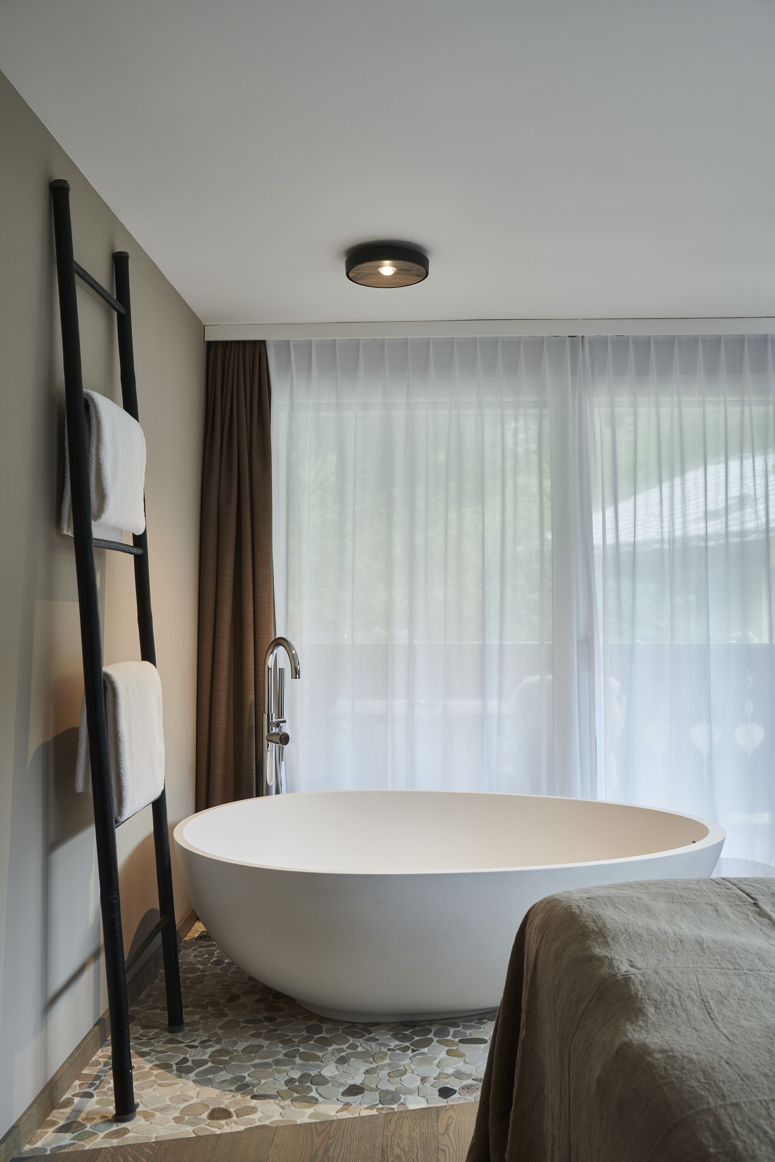 A modern bathroom with a freestanding bathtub, a towel rack, and a shower.