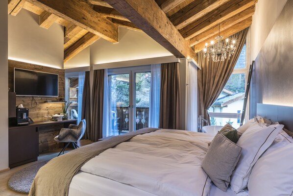 Une chambre moderne avec un grand lit, un bureau équipé d’une télévision et une vue sur l’extérieur.