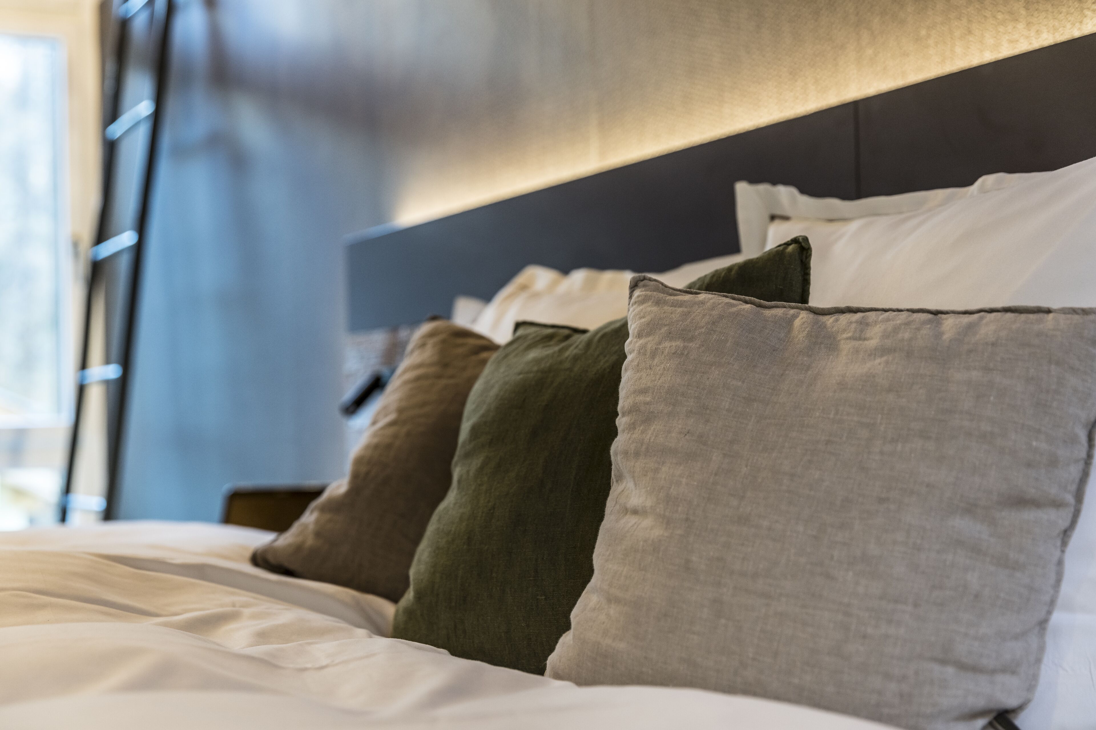 Een net opgemaakt bed met meerdere kussens in verschillende tinten.