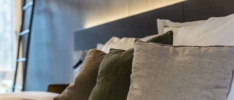 A neatly made bed with multiple pillows in various shades.