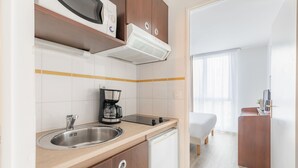 A compact kitchen with a sink, stove, and coffee maker. - Appart’City Confort Brest (Brest)