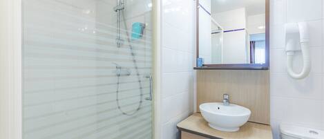 Un baño moderno con cabina de ducha de vidrio, un lavabo blanco y un espejo sobre él.
