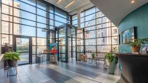 A spacious lobby with large windows, a reception desk, and potted plants. - Appart’City Confort Brest (Brest)