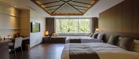 Una habitación de hotel moderna con una cama grande, un escritorio y vistas a árboles por la ventana.
