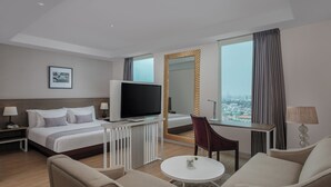 A hotel room with a bed, TV, desk, chair, and a view of the city. - PARK HOTEL Cawang - Jakarta (Jakarta)
