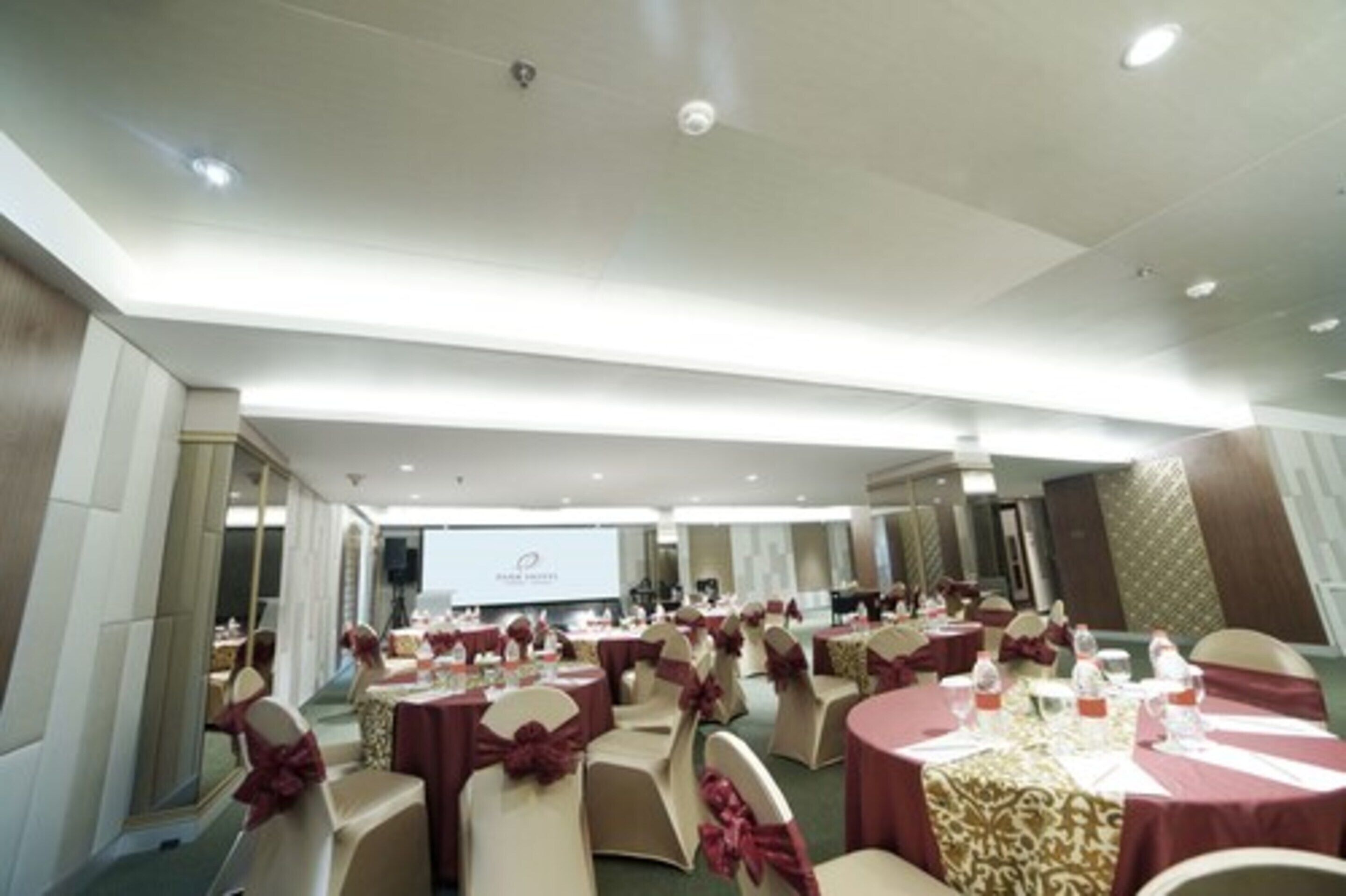 A conference room with round tables, chairs, and a projector screen.