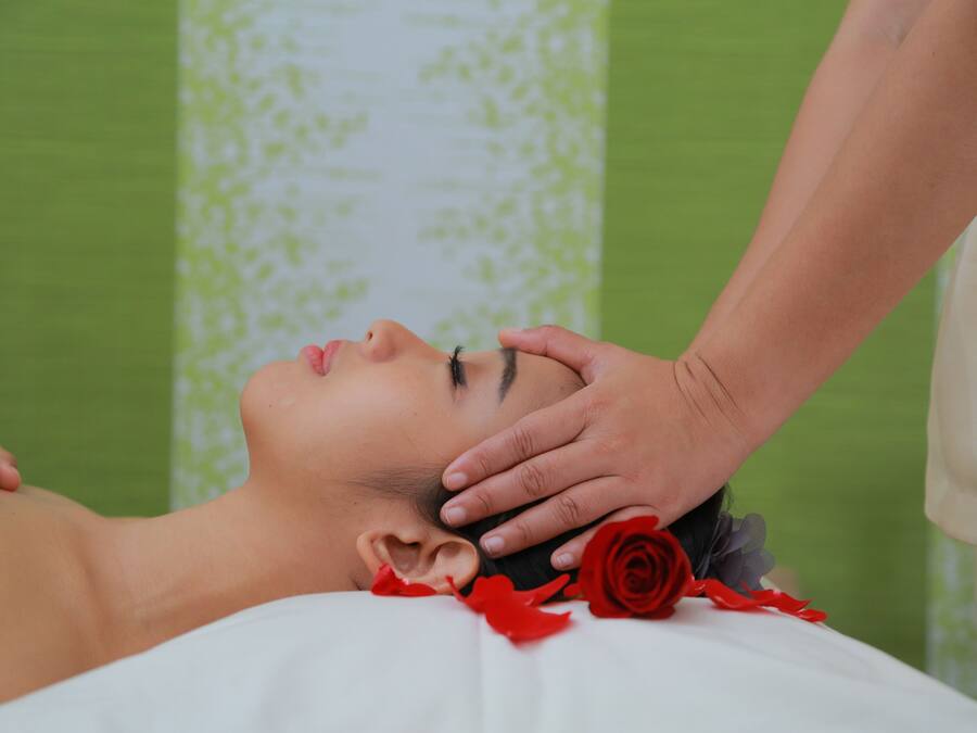 A person receiving a massage with a rose placed on their chest.