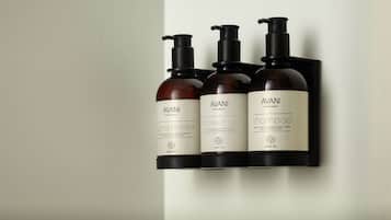 Three bottles of AVANI products on a black wall-mounted shelf.