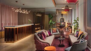 Een moderne lobby met een receptiebalie, een zithoek en een plant.
