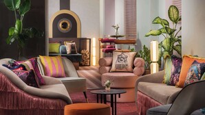 Een moderne woonkamer met een bank, fauteuils, een salontafel en decoratieve kussens.
