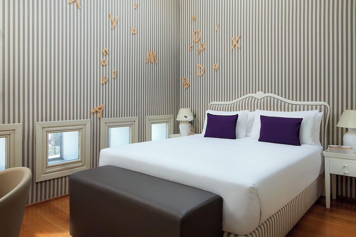 Une chambre à coucher moderne avec une lucarne, un grand lit, une table de chevet et une chaise.