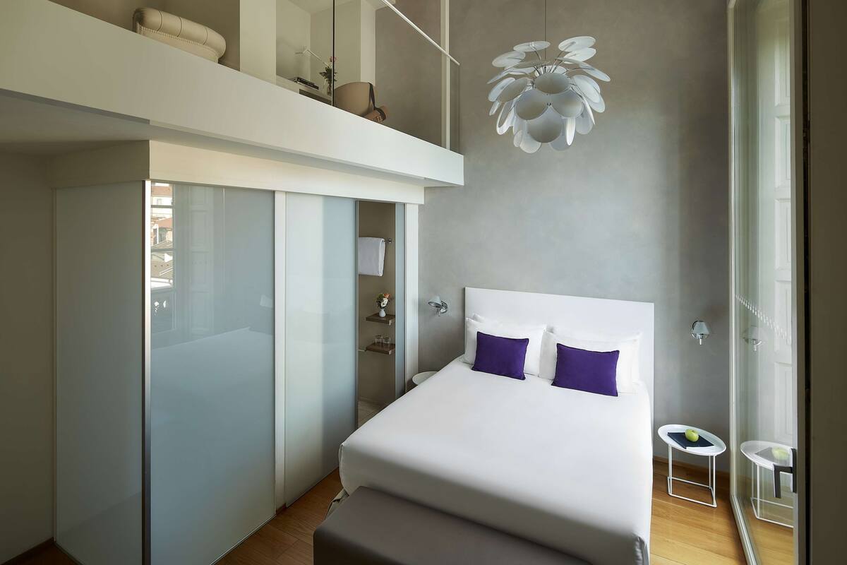 Une chambre à coucher moderne, dotée d’un grand lit, d’une armoire, d’une petite table et d’un luminaire au plafond original.