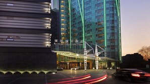 A modern hotel with a curved facade and green lighting accents. - Lake View Hotel (Beijing)
