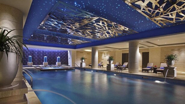A large indoor swimming pool with a starry ceiling design, lounge chairs, and potted plants. - Lake View Hotel (Beijing)