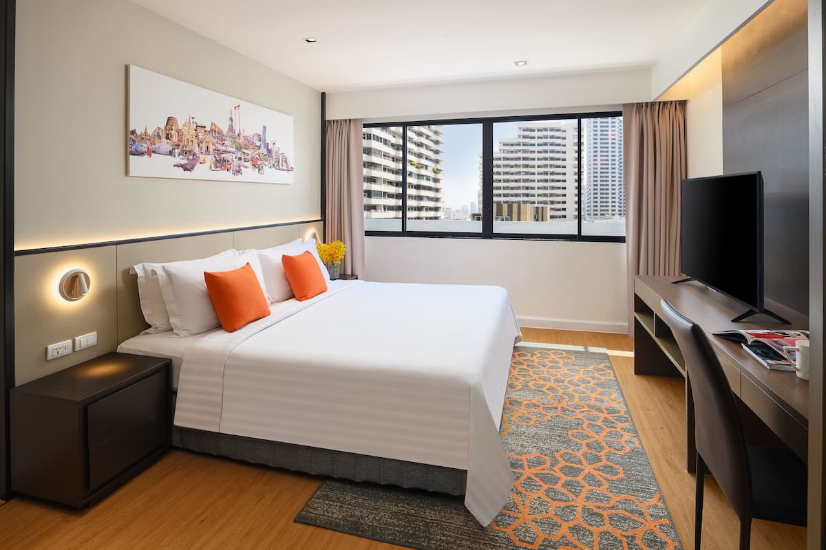 Una habitación de hotel moderna con una cama grande, televisor de pantalla plana, escritorio y vistas a la ciudad.