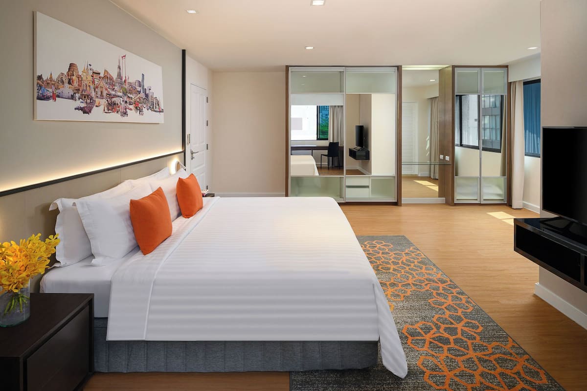 Habitación de hotel moderna con una cama grande, un televisor de pantalla plana y una obra de arte urbana en la pared.