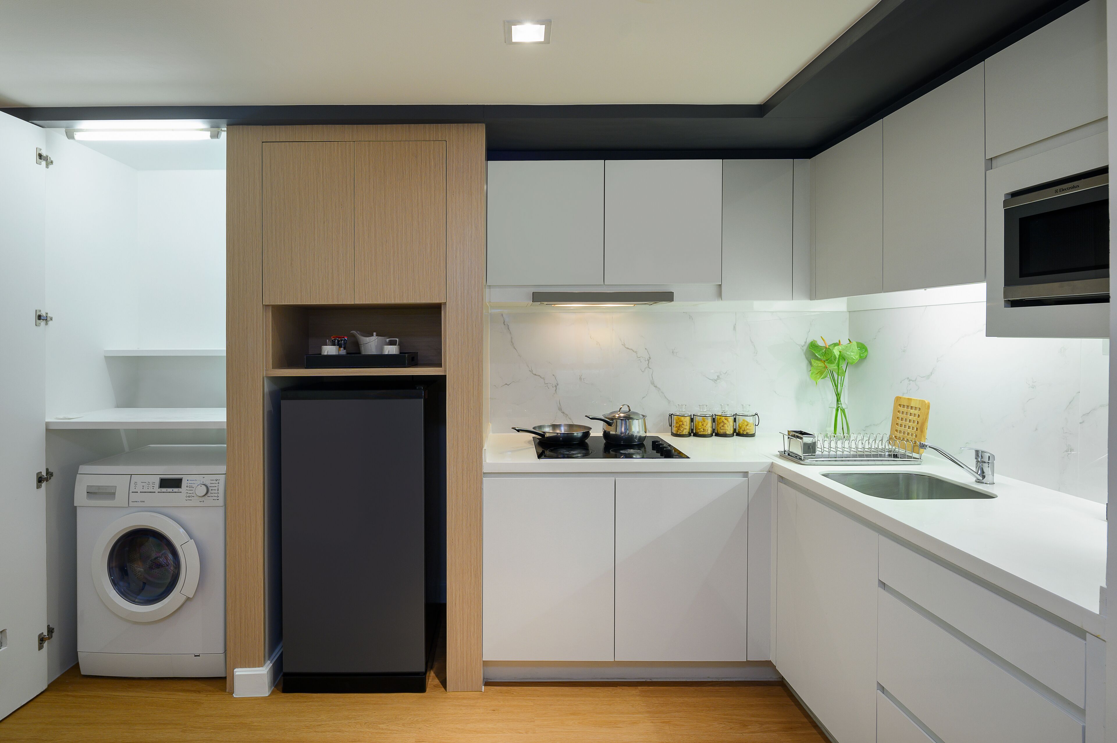 Une cuisine compacte équipée d’un lave-linge, d’un réfrigérateur, d’une cuisinière et d’un four à micro-ondes.