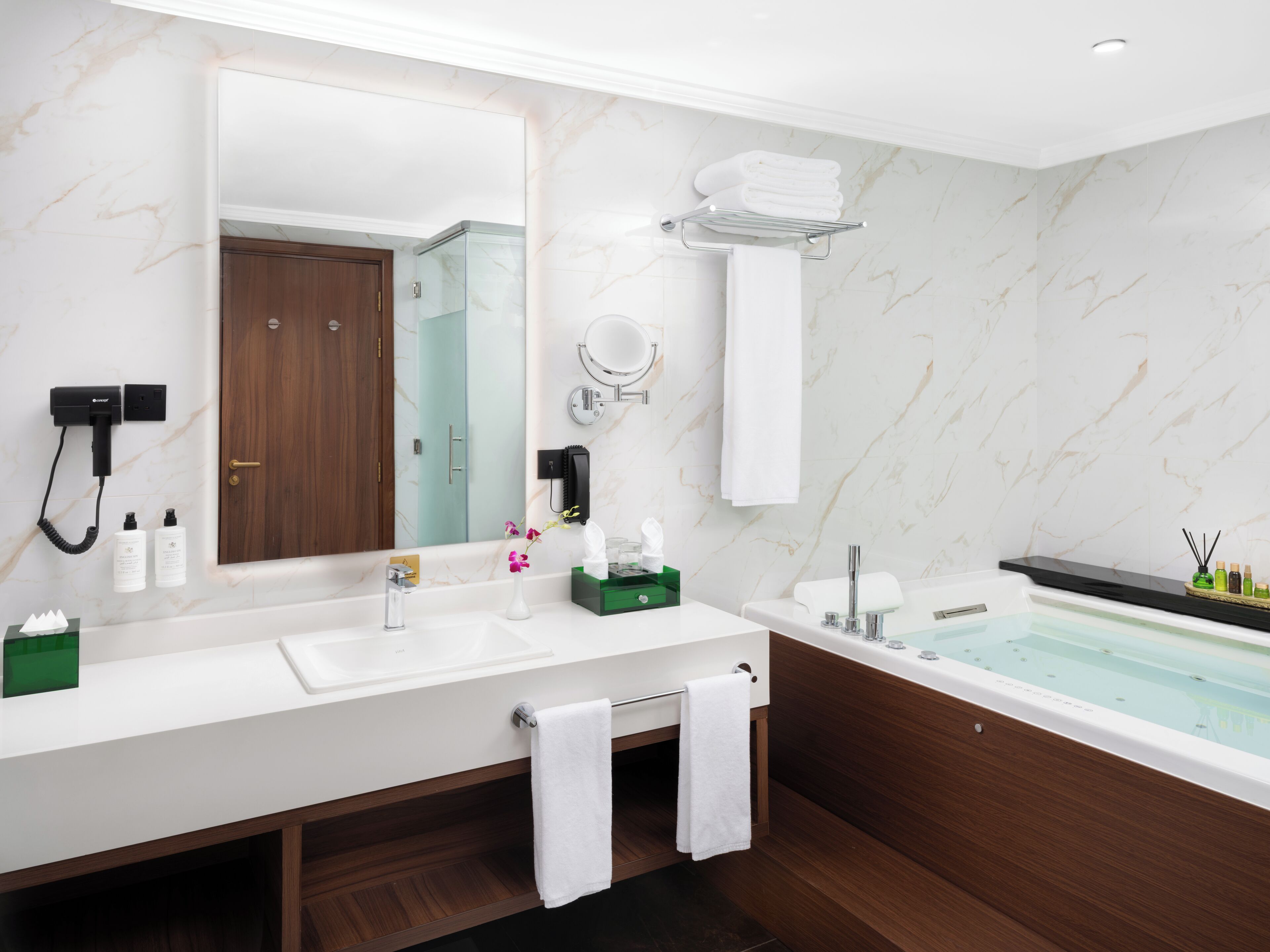 Une salle de bain moderne avec un grand miroir, deux vasques, une baignoire et un meuble-lavabo en bois.