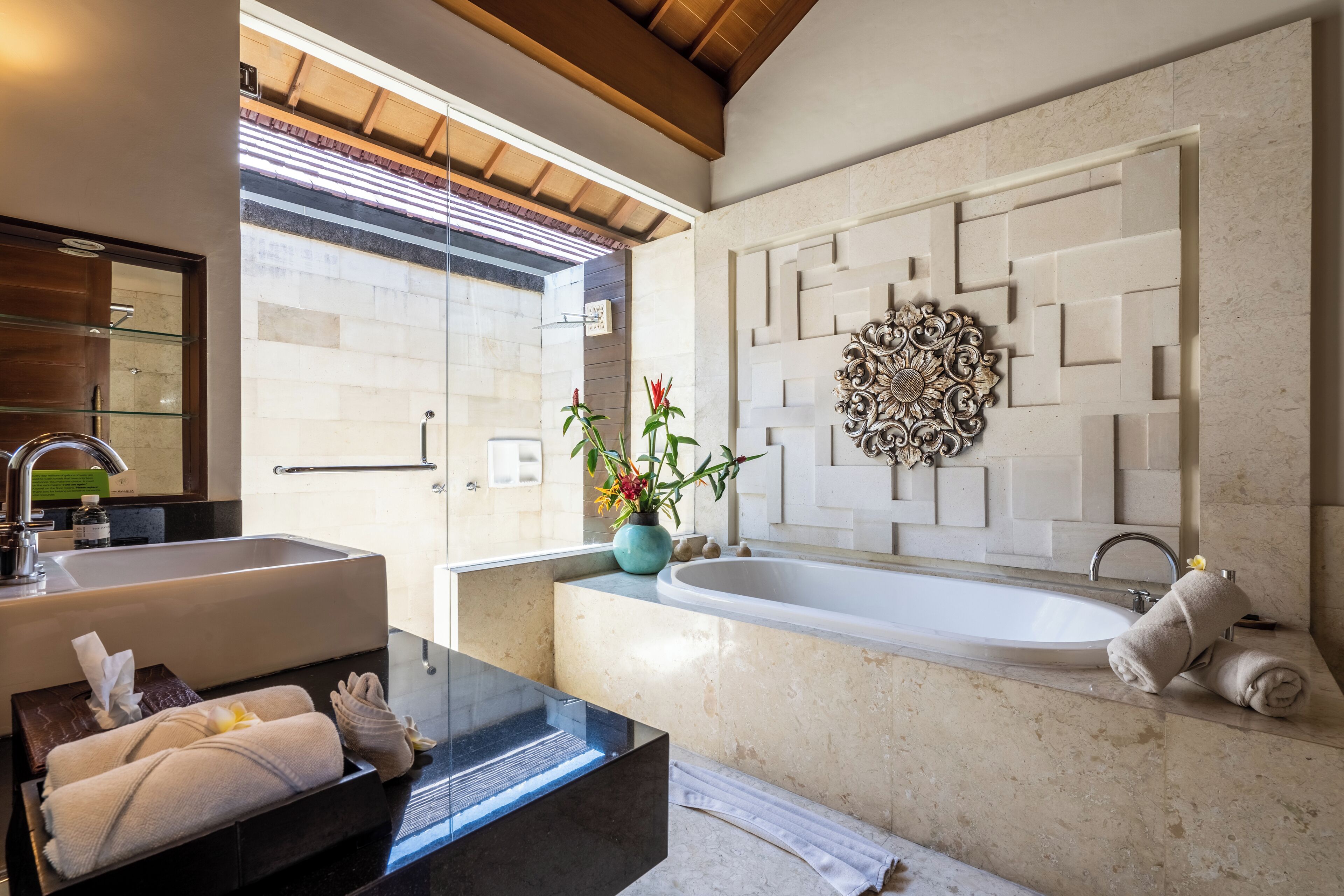 A modern bathroom with a large sink, bathtub, and decorative wall panel.