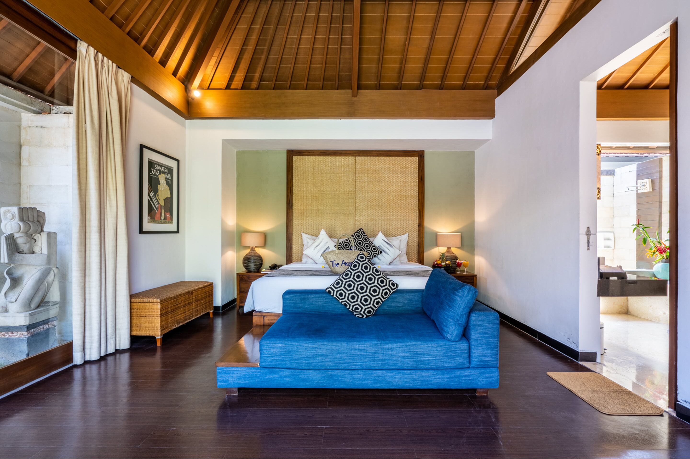 Une chambre moderne avec un grand lit, un canapé bleu et un plafond en bois.