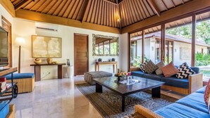 A spacious living area with a wooden ceiling, a large sofa set, a coffee table, and a television. - The Akasha Seminyak Bali Luxury Villas (Seminyak)