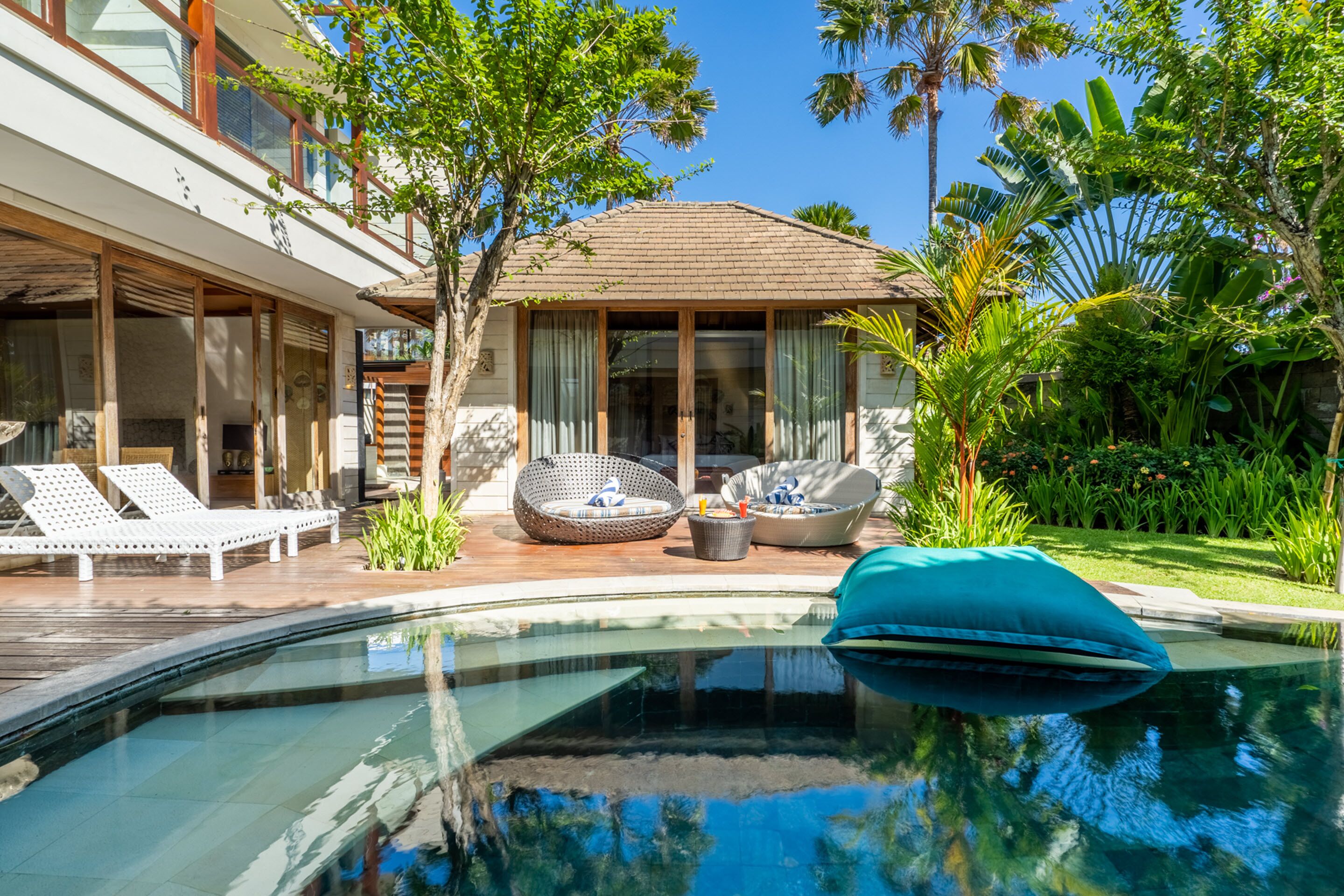 A pool area with lounge chairs and a small seating area with cushions.