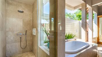 A modern bathroom with a glass-enclosed shower, a freestanding bathtub, and a view of the outdoors.