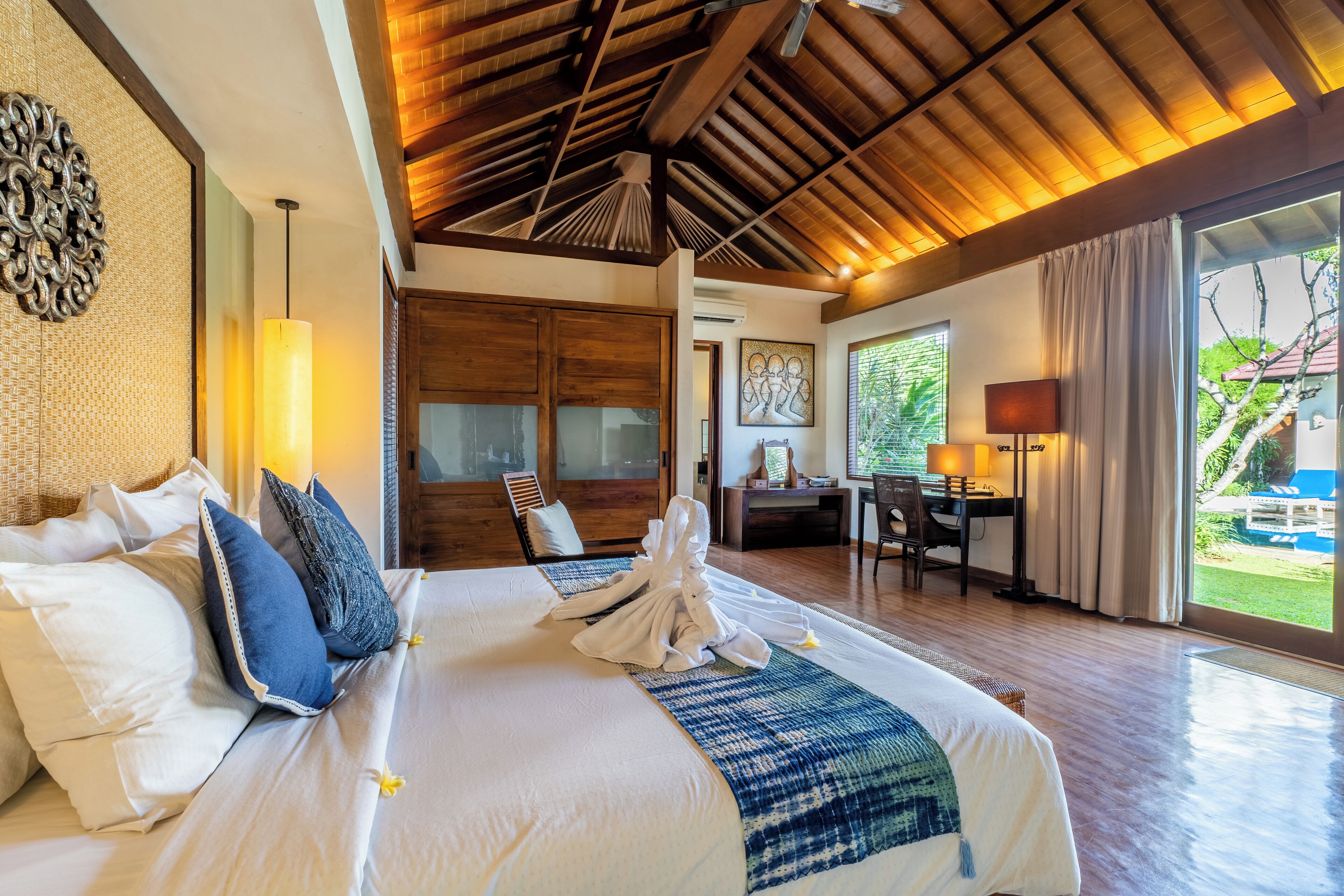 A spacious bedroom with a large bed, a desk, and a view of the outdoors.