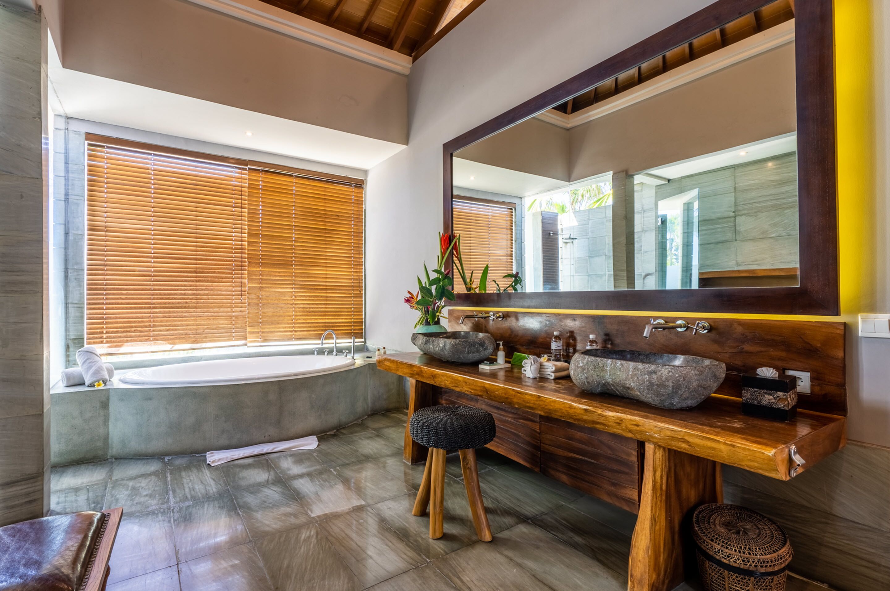 Une salle de bain moderne avec un meuble-lavabo en bois, un grand miroir et une baignoire.