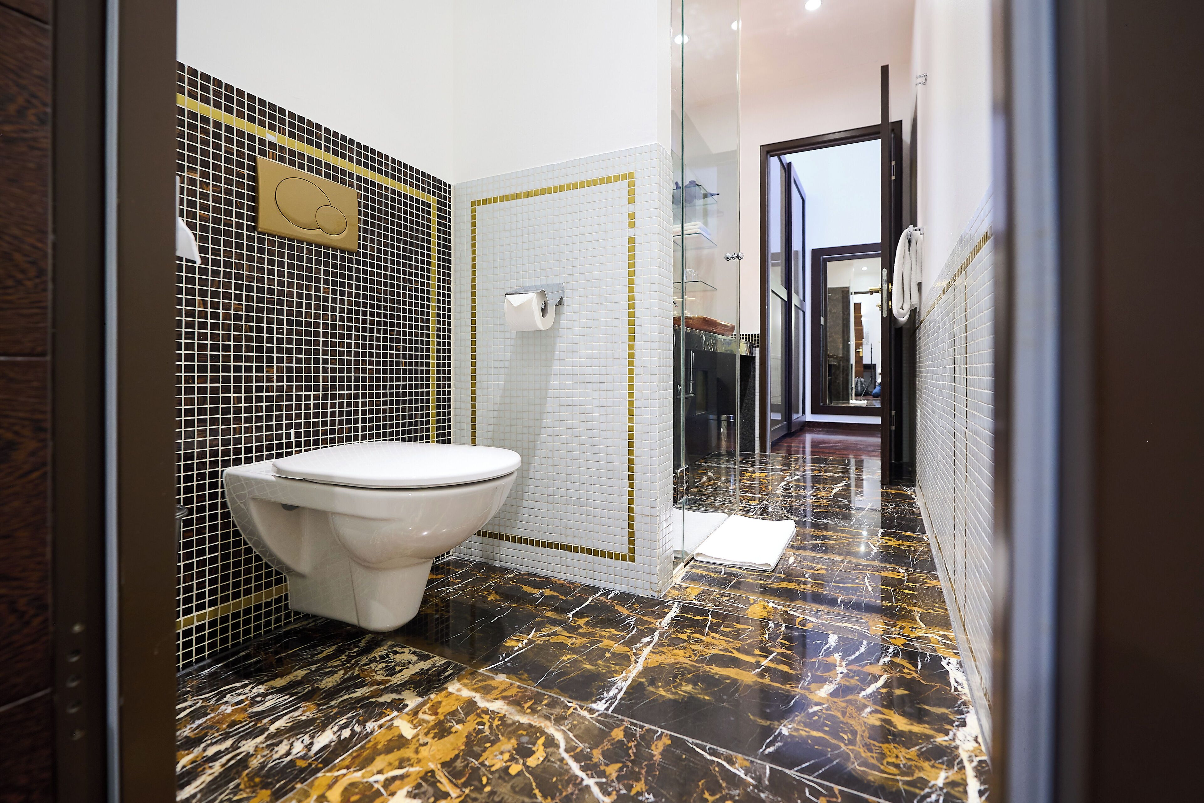 A modern bathroom with a toilet, a glass shower enclosure, and a tiled floor.
