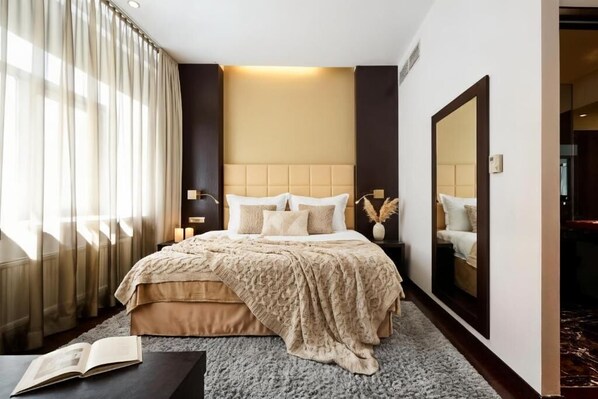 A modern hotel room with a large bed, a bedside table, a mirror, and a view of a hallway. - MyPlace Premium Apartments (Vienna)